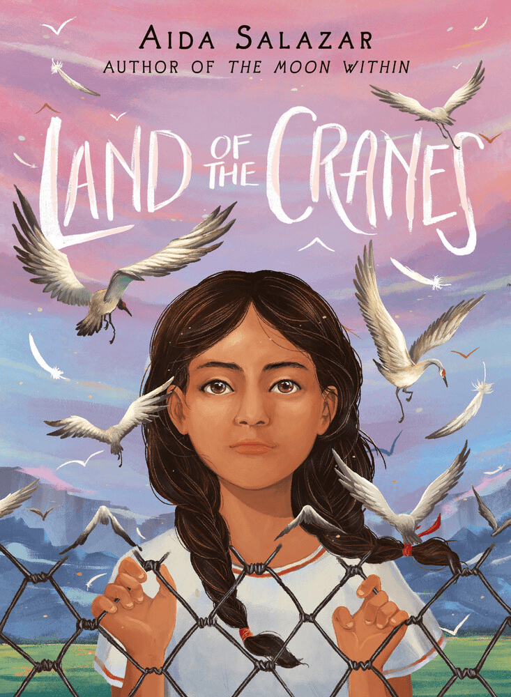 Cover of 'Land of the Cranes' by Aida Salazar, featuring a young girl with long hair gazing through a chain-link fence, surrounded by flying cranes and a colorful sky.